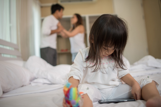 little-girl-sitting-with-her-parents-bed-looking-serious_1150-4934