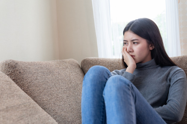 close-up-face-unhappy-asian-pretty-young-woman-sitting-alone-couch_1150-15513